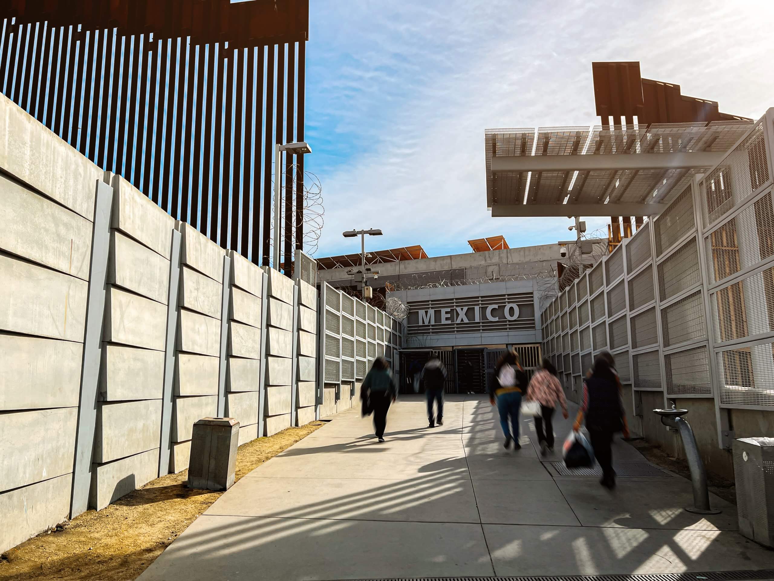 Long Shutter Image of Commuters and Tourists Walking toward a “Mexico” Sign at the Border into Tijuana Mexico from the United States